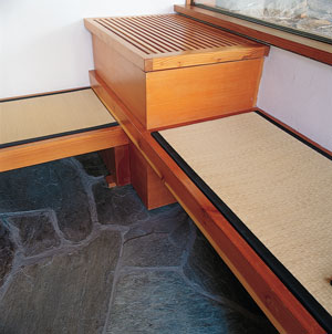 The control panel for an outdoor hot tub, which serves as the soaking tub, is cleverly concealed next to the tatami-mat benches.